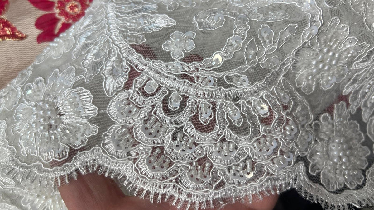 FR : Motifs floraux et arabesques perlées sur tulle blanc. EN: Beaded flowers and scroll motifs on white tulle.