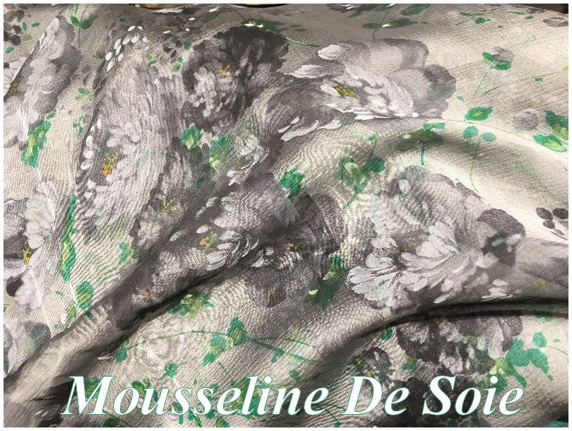 Gasa de seda de alta costura con estampado de flores negras, verdes y grises sobre fondo gris por metro.