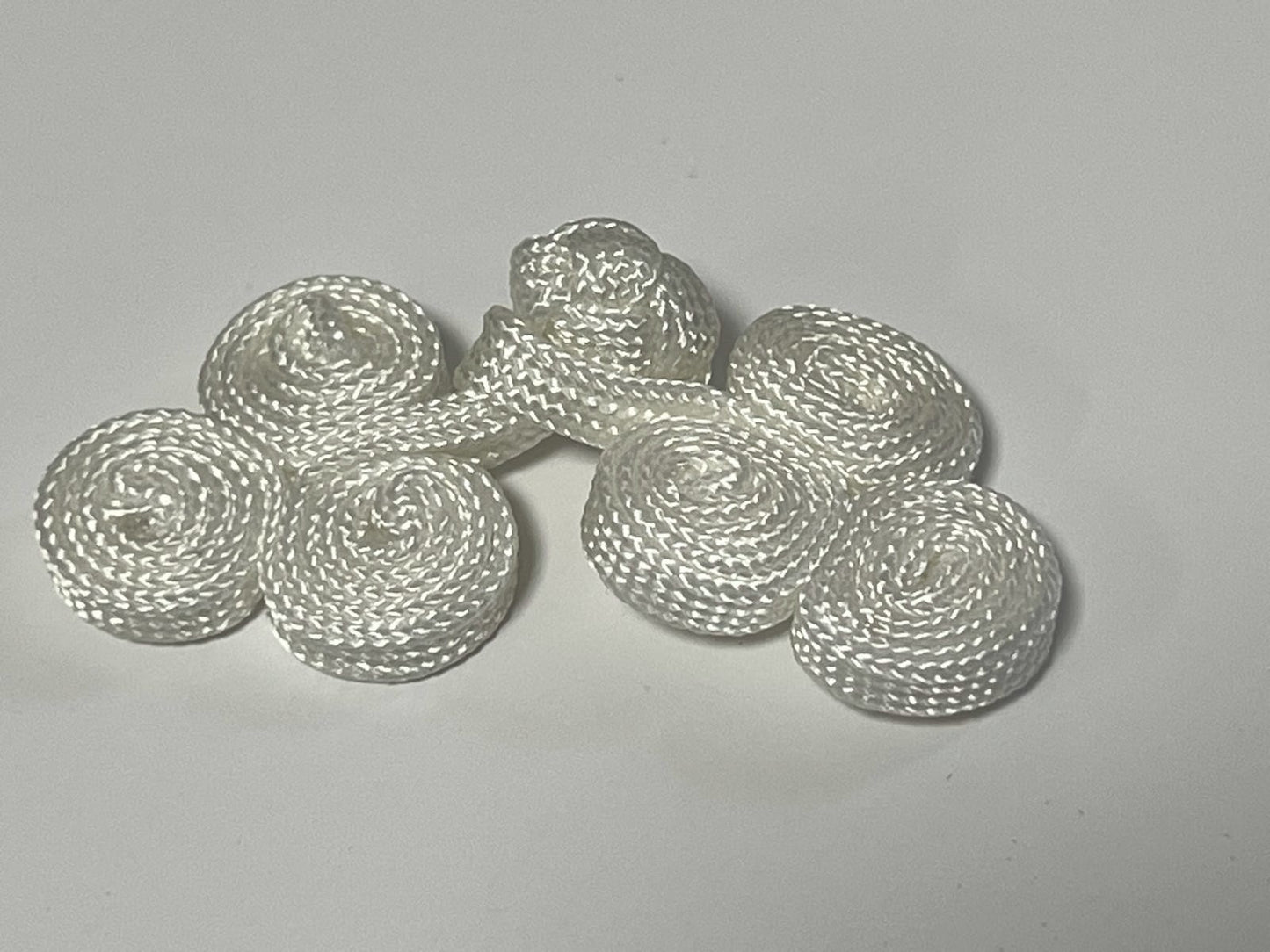 Attaches en brandebourg Blanc : l'élégance d'une fermeture traditionnelle