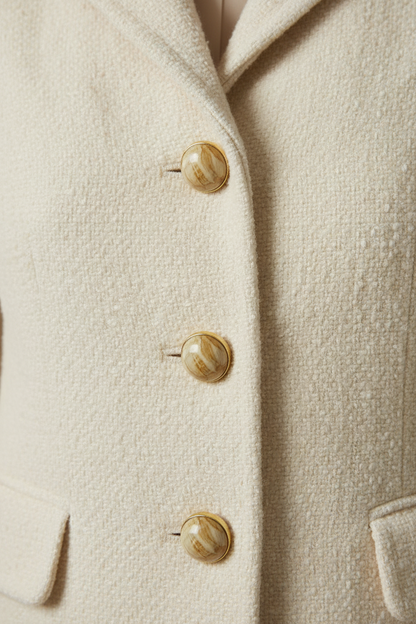 Bouton haute couture dôme marbré or – gros plan sur veste ivoire